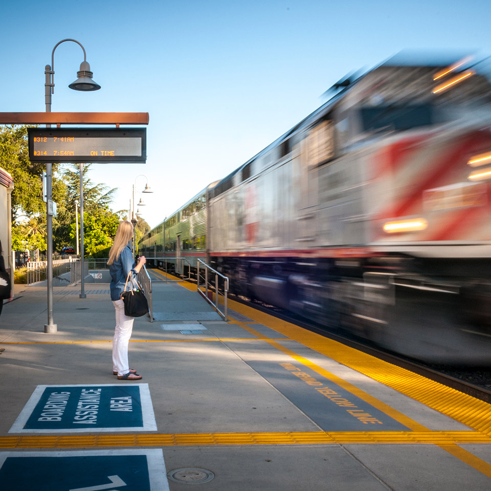 Person waiting at a train station as a train arrives